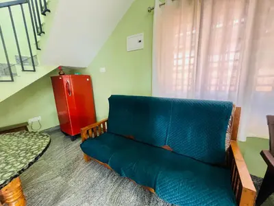 a living room with a blue couch and a red refrigerator at AGNEYA Holiday Home in Wayanad