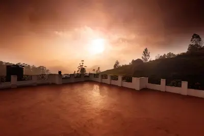 a sunset over a white fence with the sun in the sky at Hillside haven ooty in Ooty