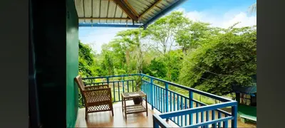 a balcony of a house with two chairs and trees at Hilarious Garden Ooty in Ooty