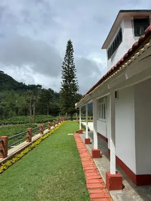 a building with a pathway next to a grass yard at Ellem House in Kotagiri