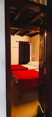 a bedroom with two beds with red sheets and a window at Wildora Junglevilla Wayanad in Chekadi