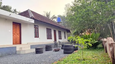 a white house with a porch and chairs in front of it at Wildora Junglevilla Wayanad in Chekadi
