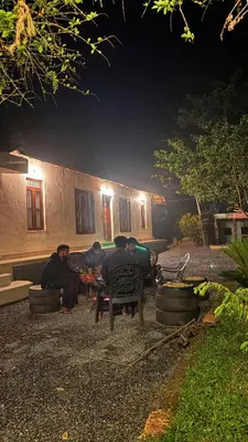 a group of people sitting outside of a house at night at Wildora Junglevilla Wayanad in Chekadi