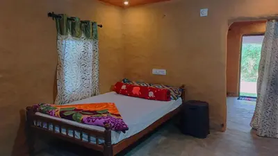 a bedroom with a bed with curtains and a window at Mud bees resort in Kanthalloor