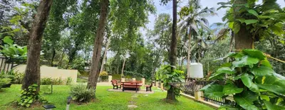 a park with a bench and a table and trees at Pochans Zen in Thattakād