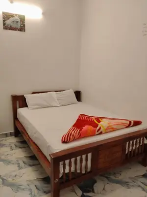 a bed with a wooden frame with a blanket on it at Nakshatra Home Stay in Vattavada