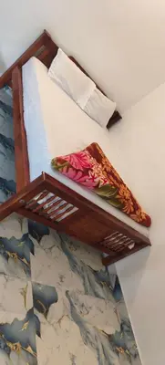 a bed with a wooden shelf on the wall at Nakshatra Home Stay in Vattavada