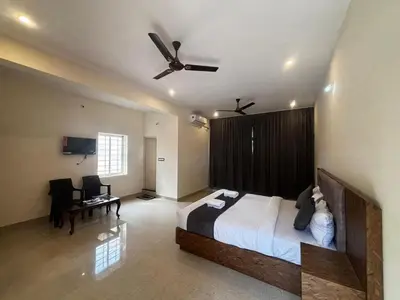 a bedroom with a bed and a ceiling fan at Surabhi Comforts Inn in Mysore