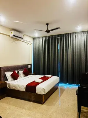 a bedroom with a bed and a window with curtains at Surabhi Comforts Inn in Mysore