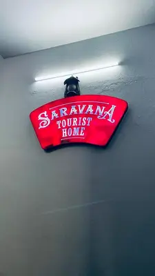 a red sign hanging from a ceiling with a light at Saravana tourist home in Kozhikode