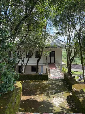 a white house with trees in front of it at Silver Rock Cottage Valparai in Vālpārai