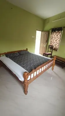 a large wooden bed in a room with a chair at Silver Rock Cottage Valparai in Vālpārai