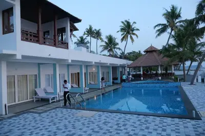 a man standing next to a swimming pool next to a building at Breakwater Palace in Cochin