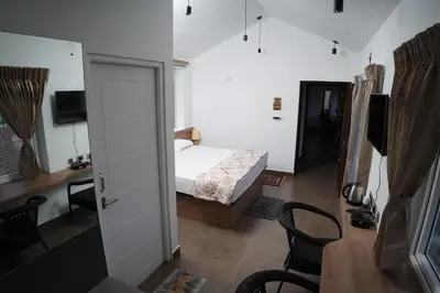 a bedroom with a bed and a desk and a table at Jacaranda Home Stay in Kotagiri