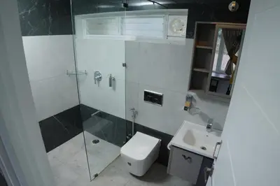 a bathroom with a shower and a toilet and a sink at Jacaranda Home Stay in Kotagiri