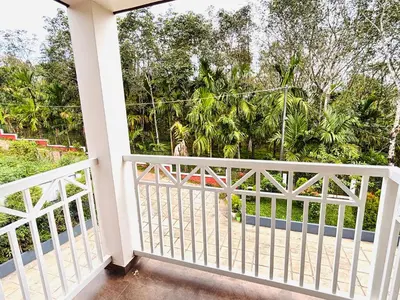 a balcony with a white fence and trees at Tanis serenity in Meenangadi