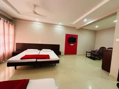 a bedroom with two beds and a red door at Chandragiri INN in Kalpetta
