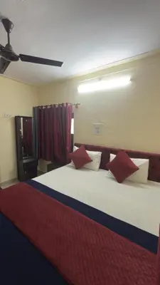 a bedroom with a large white bed with red pillows at Roshan's Welcome Home Stay in Mysore