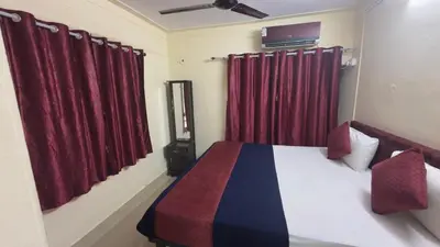 a bedroom with a bed with red curtains at Roshan's Welcome Home Stay in Mysore