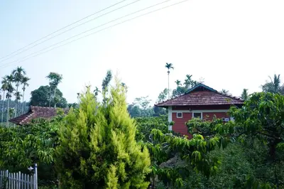 a red house in the middle of a field of trees at Stay with Lakeview Ponnampet in Ponnampet