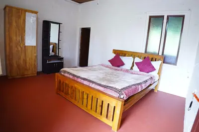 a bedroom with a wooden bed with red pillows at Stay with Lakeview Ponnampet in Ponnampet