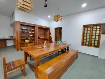 a dining room with a wooden table and benches at AANMEEZ Homestay in Kuthuparamba