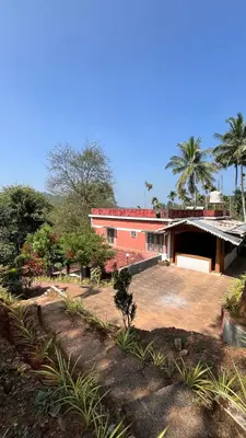 a red brick building with a courtyard and palm trees at Spillway private pool villa in Meenangadi