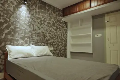 a bedroom with a bed and a stone wall at Vista Chembra Service Apartment 20A in Meppādi