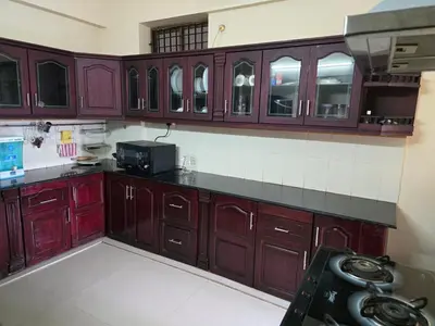 a kitchen with dark wood cabinets and a microwave at The Western Castle Apartment - 2BHK Apartment in Kannur