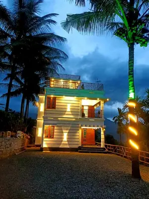 a house with a palm tree in front of it at Paalm view premium resort in Kanthalloor
