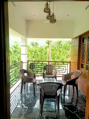 a patio with chairs and a table on a balcony at Paalm view premium resort in Kanthalloor