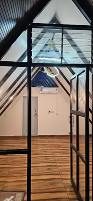 an attic room with a glass door and a wooden floor at Ambience Retreat in Sivasamudram