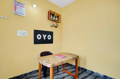 a small table in a room with a sign on the wall at Hotel O Nimishamba Residency in Mysore