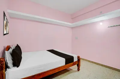 a bedroom with a bed with white walls at Hotel O Nimishamba Residency in Mysore