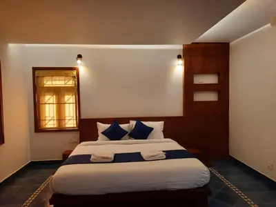 a bedroom with a large bed with blue and white pillows at Petrus Signature Villa in Sultan Bathery