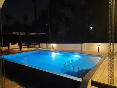 a large blue swimming pool at night at Petrus Signature Villa in Sultan Bathery