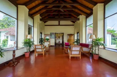 a lobby with chairs and tables and windows at amã Stays & Trails - Cottabetta Bungalow, Coorg in Gonikoppal