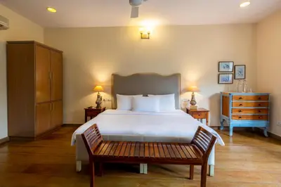 a bedroom with a large bed and a wooden bench at amã Stays & Trails - Taneerhulla Bungalow, Coorg in Titimati