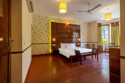 a bedroom with a bed and a table and chairs at amã Stays & Trails - Taneerhulla Bungalow, Coorg in Titimati