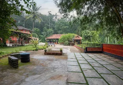 a courtyard in a park with a building and trees at Enteveedu Homestay in Panamaram