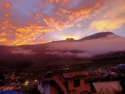 a sunset over a city with a fog covered mountain at Vattavada Homestay in Vattavada