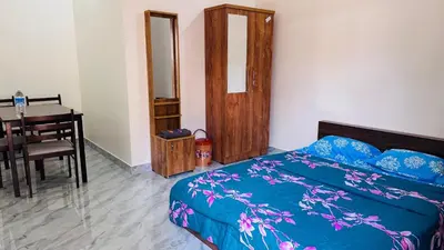 a bedroom with a bed and a table and a desk at Chemperi Residency in Paithalmala