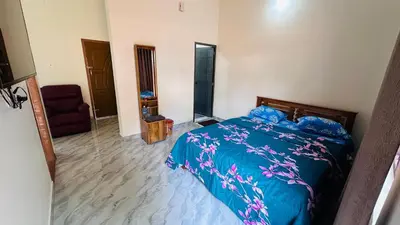 a bedroom with a bed with a blue comforter and a chair at Chemperi Residency in Paithalmala
