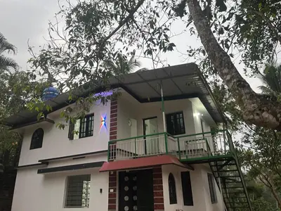 a white house with a balcony and a tree at VY3 Homes in Vythiri