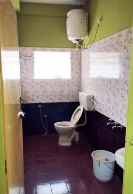 a bathroom with a toilet and a window at VR Home Stay Ooty in Ooty