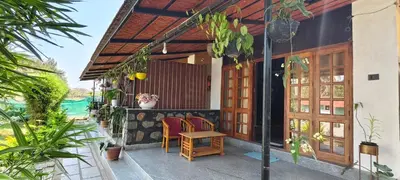 a porch of a house with a table and chairs at Elephant County Resort in Masinagudi