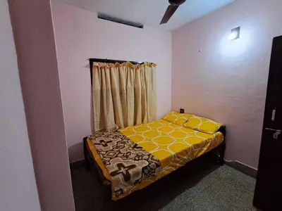 a small bedroom with a bed with a yellow blanket at A-Kutty in Irinjālakuda