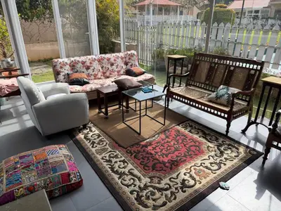 a living room with a couch and chairs and a rug at Neom Valley Stays in Ketti