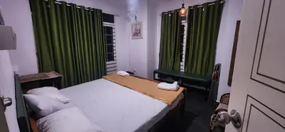 a bedroom with a bed and a window with green curtains at Kodamukku water front cottage in Trichūr