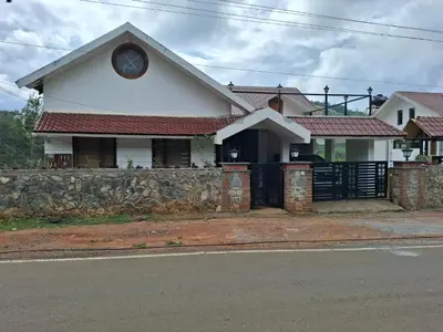 a white house with a stone retaining wall at Mandarin Orchid Resort in Kotagiri